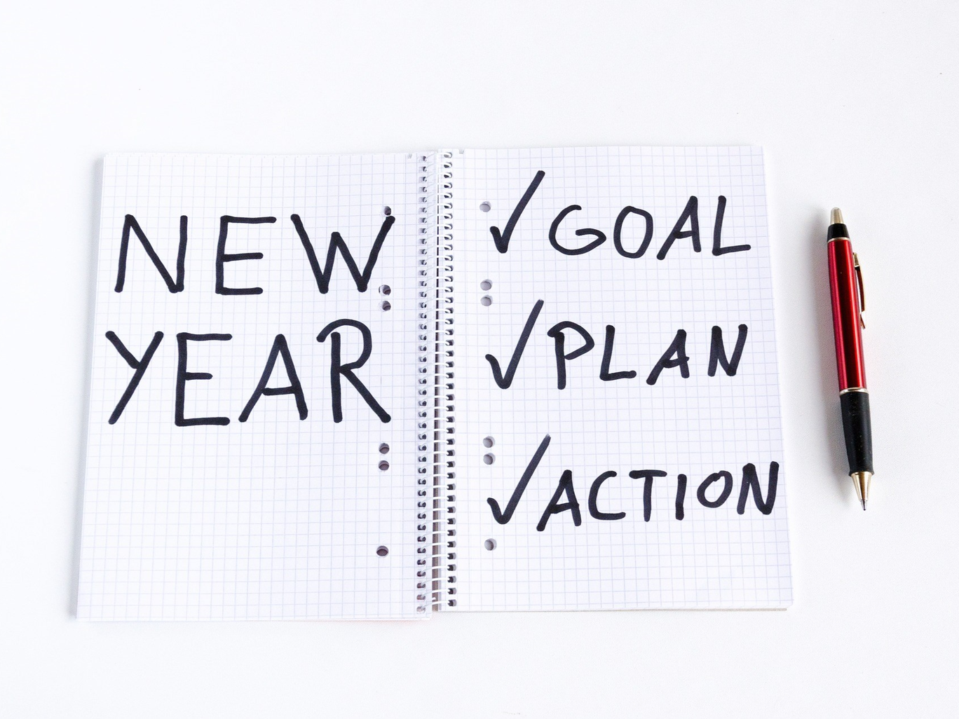 An open notebook that says: new year, goal, plan, action.